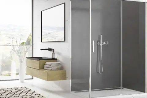 Salle de bain moderne avec paroi de douche en plexiglas fumé, meuble vasque en bois, et vue panoramique.