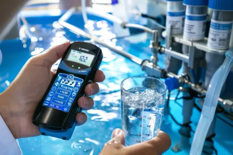 Analyse de la qualité de l'eau potable à Rouen. Un appareil de mesure est tenu au-dessus d'un verre d'eau.