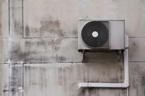 Unité extérieure d'une pompe à chaleur installée sur un mur en béton. Le système est prêt à fonctionner.