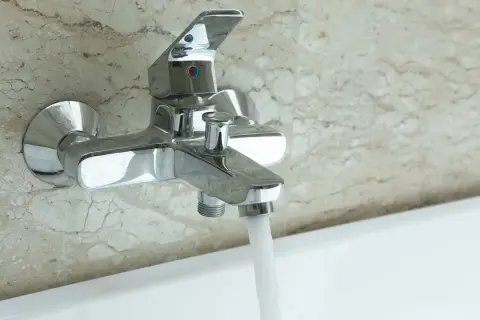 Robinet de baignoire mural chromé, prêt à installer, avec eau coulant doucement.