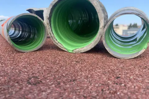 Trois tuyaux en PVC, dont un avec un revêtement vert vif, prêts pour enlever calcaire canalisation pvc.