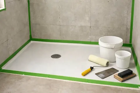 Préparation d'une douche : un receveur en résine, des seaux, un rouleau et une spatule. L'inconvénient ? La préparation minutieuse.