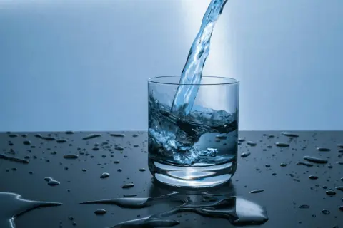 Verre d'eau versé, éclaboussures sur la table. L'eau calcaire peut causer du mal de ventre.