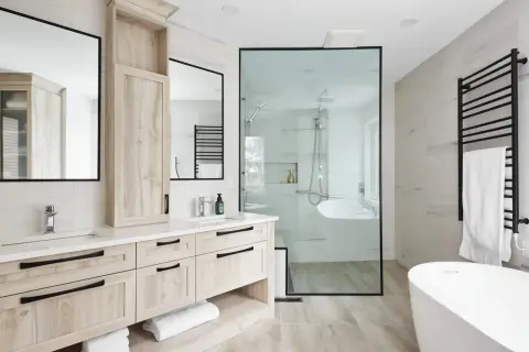 Salle de bain moderne avec double vasque, douche vitrée et baignoire. L'installation plomberie salle de bain est soignée, avec des robinetteries chromées et un sèche-serviettes noir.