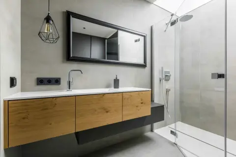 Meuble de salle de bain en bois avec une belle profondeur, miroir, robinetterie moderne et douche vitrée.