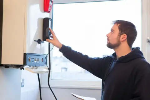 Un technicien ajuste la commande d'une chaudière à condensation.